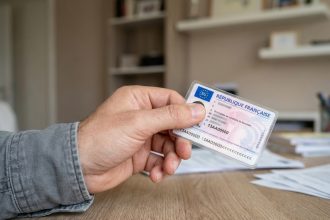 Main tenant un permis de conduire français montrant le numéro de permis visible sur la carte plastifiée